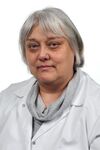 Porträtfoto einer Frau mit grauen, kurzen Haaren. Sie trägt weiße medizinische Kleidung und lächelt freundlich in die Kamera.
